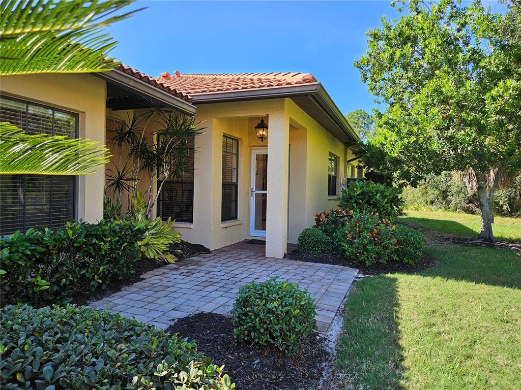 A paved walkway leads to the recessed front entrance of a yellow stucco house — 4528 CANCELLO GRANDE AVENUE, VENICE, FL