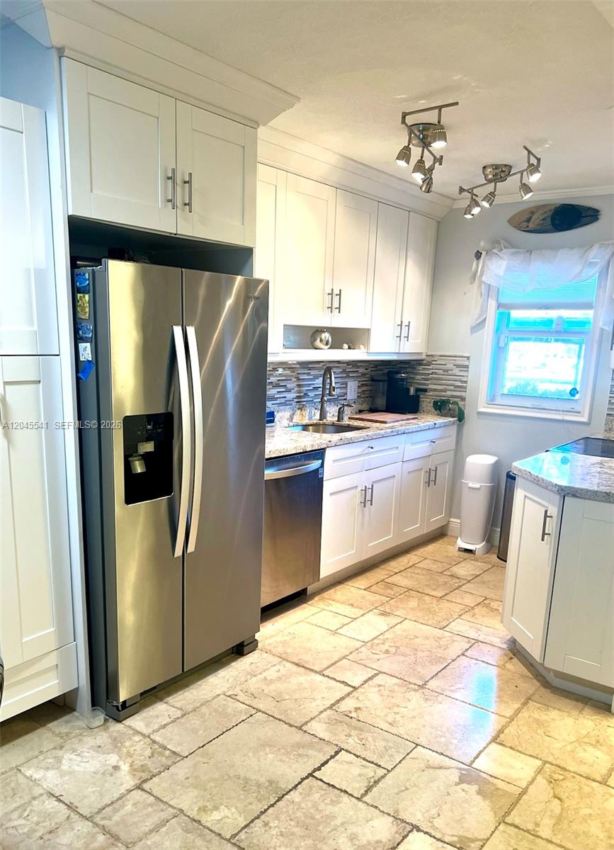 A kitchen features white cabinets, stainless steel appliances, granite countertops, and stone tile flooring — 689 NE 6th Ct # 1080, Boynton Beach FL 33435, BOYNTON BEACH, FL