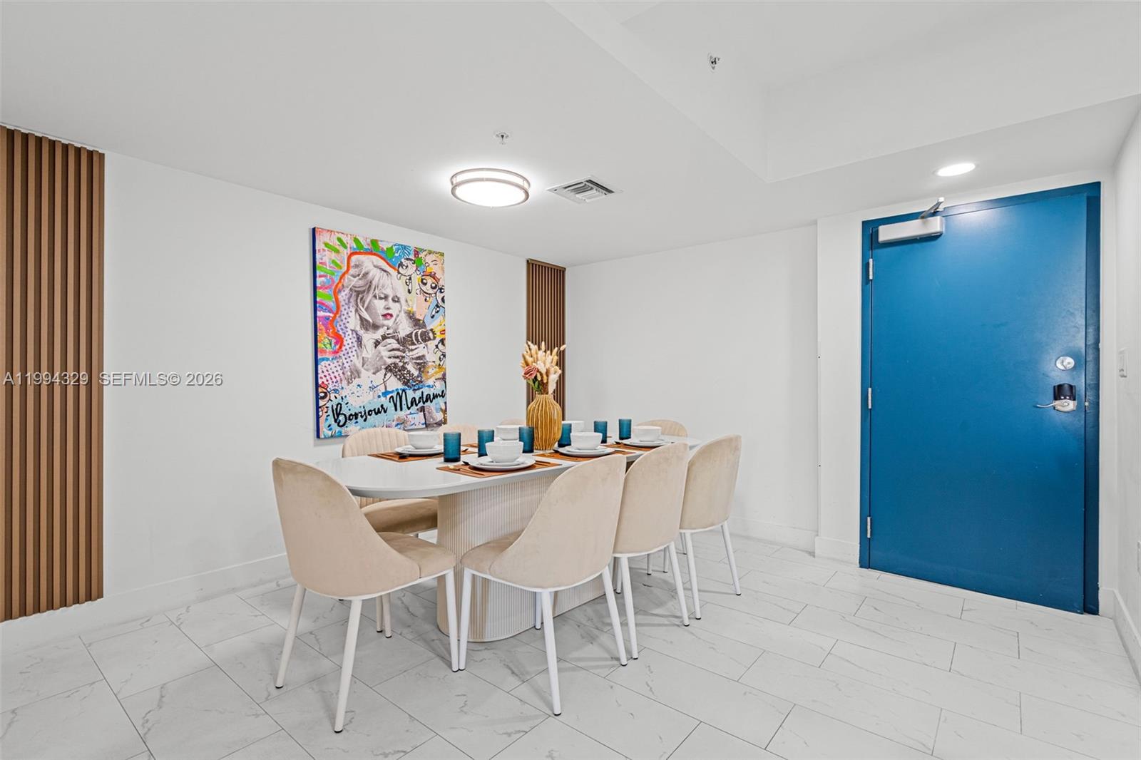 A dining room features a white oval table, beige chairs, and a colorful wall painting — 1850 Monroe St # 310, Hollywood FL 33020, HOLLYWOOD, FL