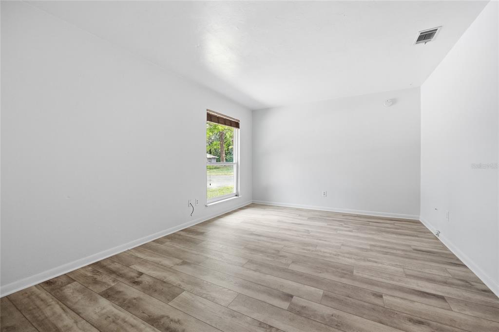 An empty room with white walls, light wood-look flooring, and a single window — 5929 NW 23 TERRACE, GAINESVILLE, FL