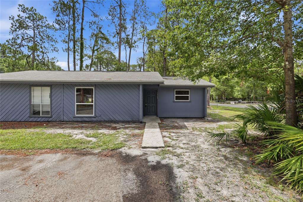 A single-story gray house with a diagonal wood-paneled exterior and a concrete walkway — 5929 NW 23 TERRACE, GAINESVILLE, FL