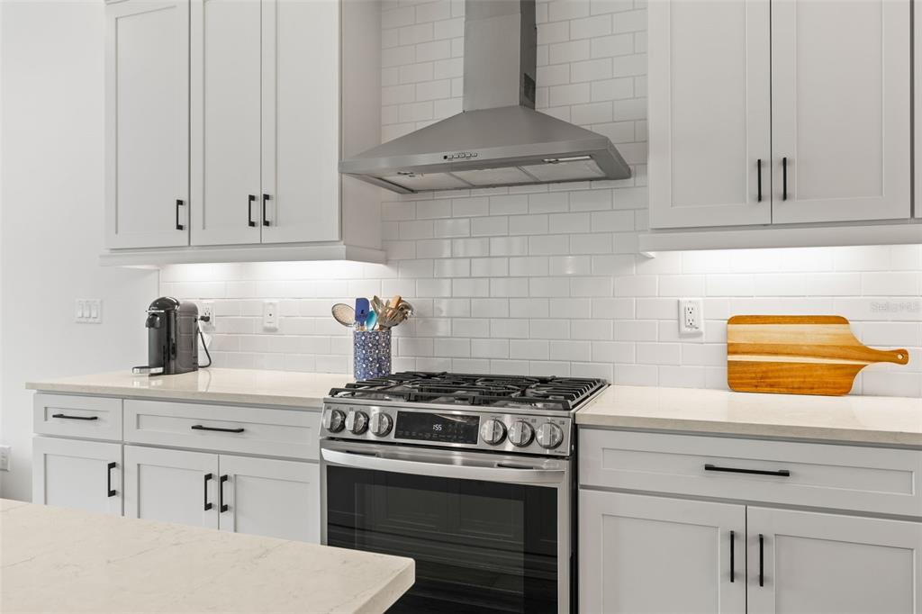 A modern kitchen features white cabinetry, a stainless steel range, and a subway tile backsplash — 3541 GREAT BANYAN WAY, WESLEY CHAPEL, FL