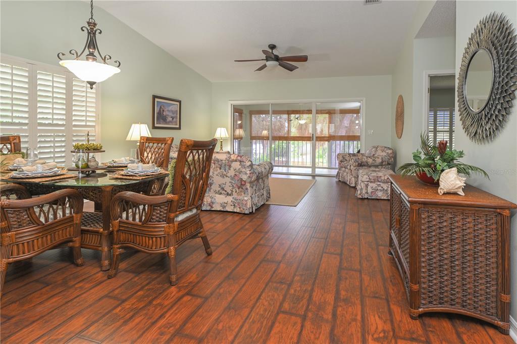 A dining area and living room with wood-look tile floors and a glass sliding door — 11300 HARBOR WAY UNIT 1731, LARGO, FL