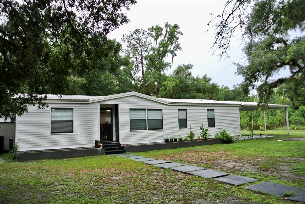 A single-story manufactured home with white siding, a metal roof, and a front walkway — 38122 CENTRAL AVENUE, ZEPHYRHILLS, FL