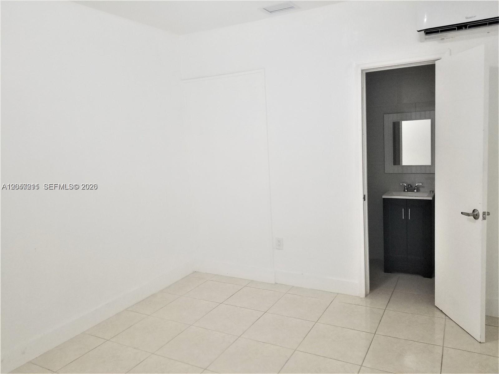 A white room with tiled floors features an open doorway leading to a small bathroom — 1829 NW 4th St # 2, Miami FL 33125, MIAMI, FL