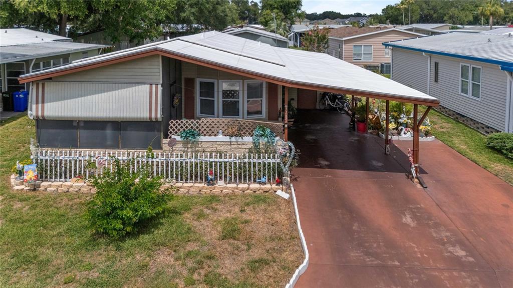 An elevated view of a manufactured home with a carport, white fence, and front yard — 3145 GREAT OAK STREET, WESLEY CHAPEL, FL