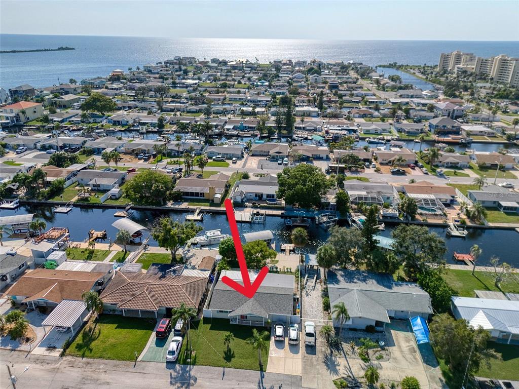 An aerial view shows a residential neighborhood with a canal leading to a large bay — 13625 MARIA DRIVE, HUDSON, FL