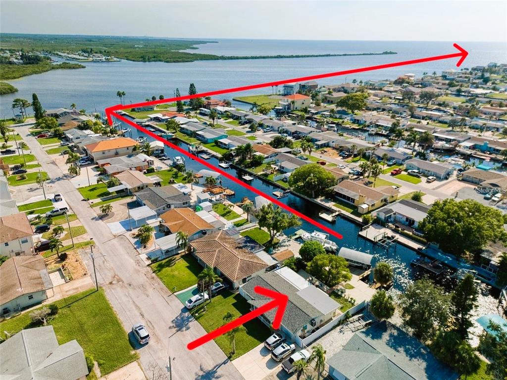 An aerial view shows a single-story house with a red door and a canal behind it — 13625 MARIA DRIVE, HUDSON, FL