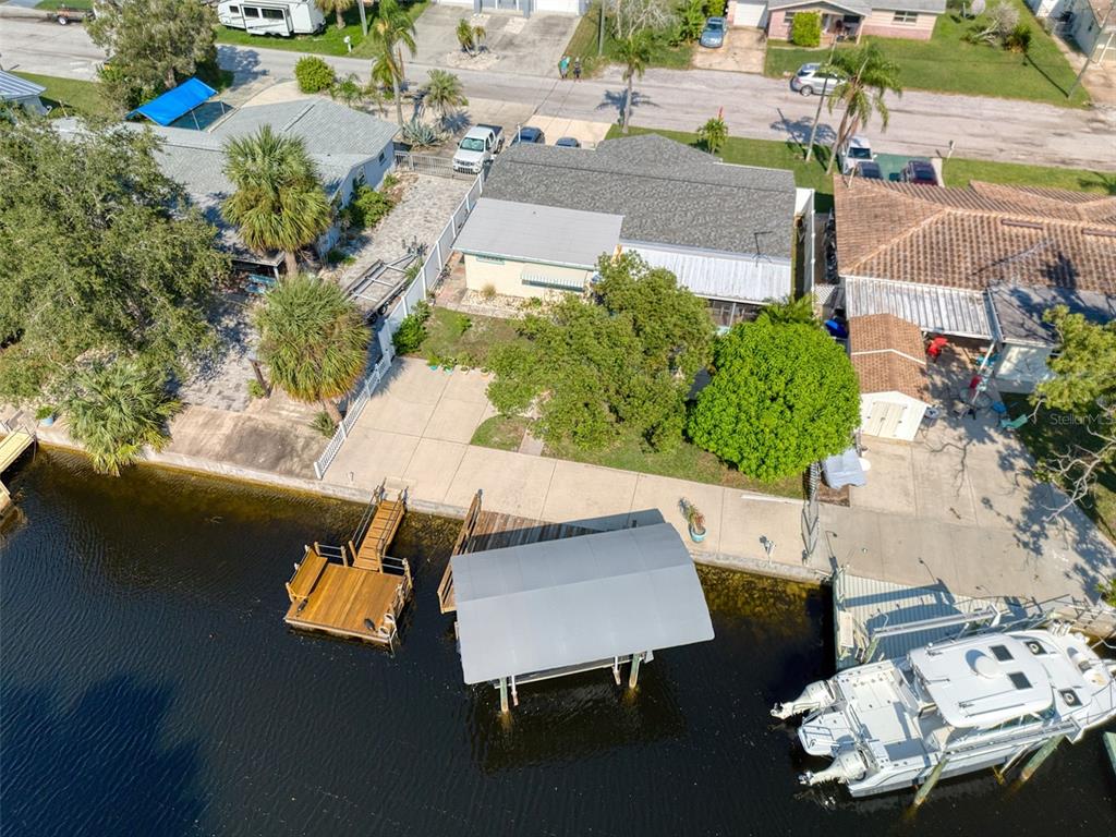 An aerial view shows a waterfront house with a boat dock, lift, and concrete patio — 13625 MARIA DRIVE, HUDSON, FL