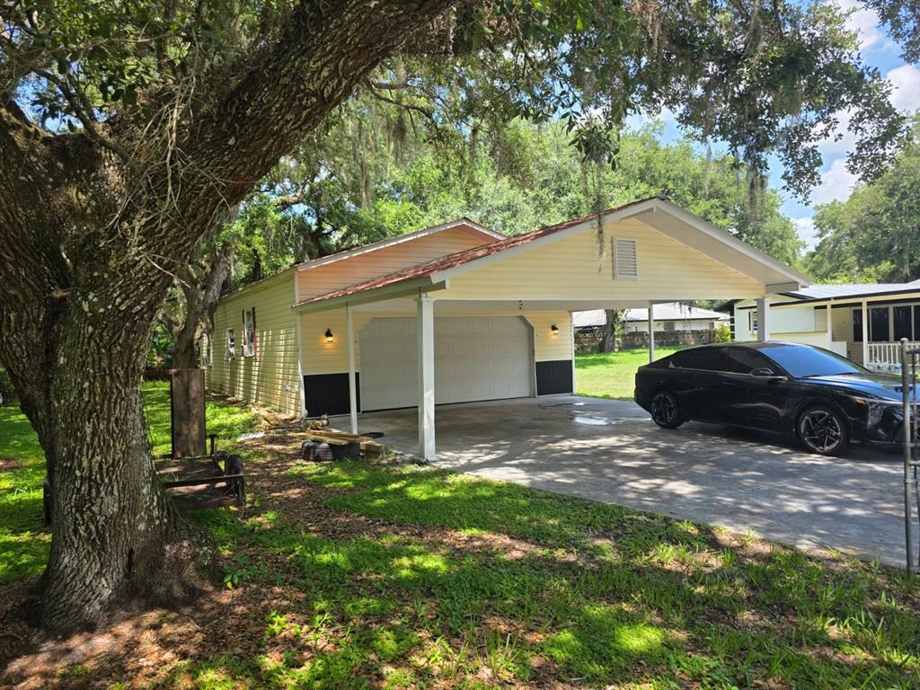 A yellow detached garage with a large carport and a black car parked underneath — 2428 SW 18TH COURT, OKEECHOBEE, FL