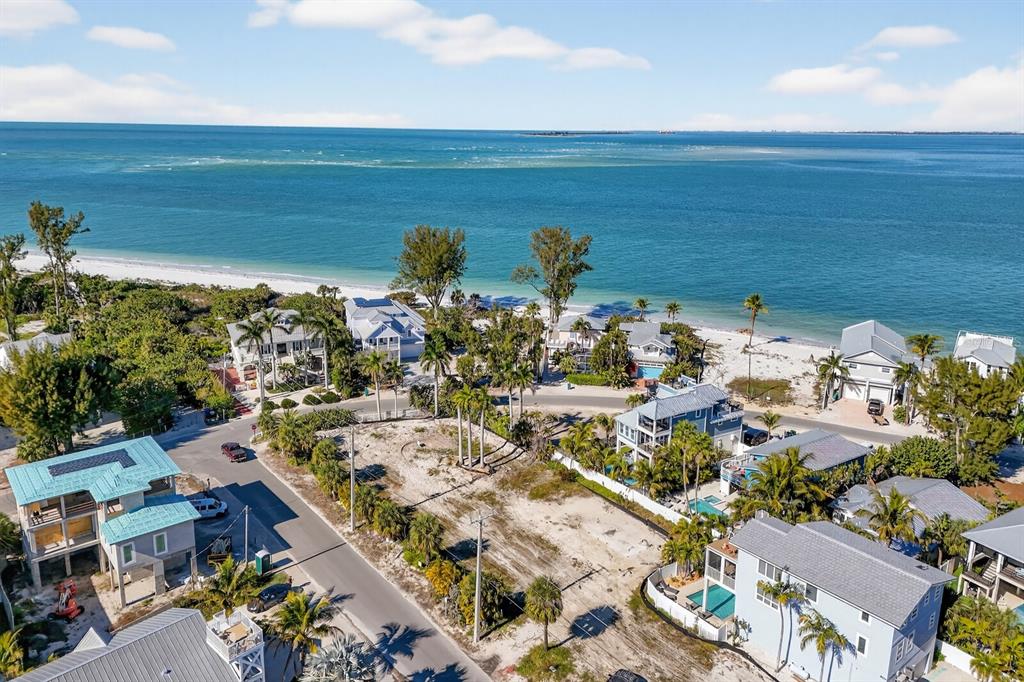 An aerial view shows a vacant coastal lot surrounded by houses near a sandy beach — 812 N BAY BOULEVARD, ANNA MARIA, FL