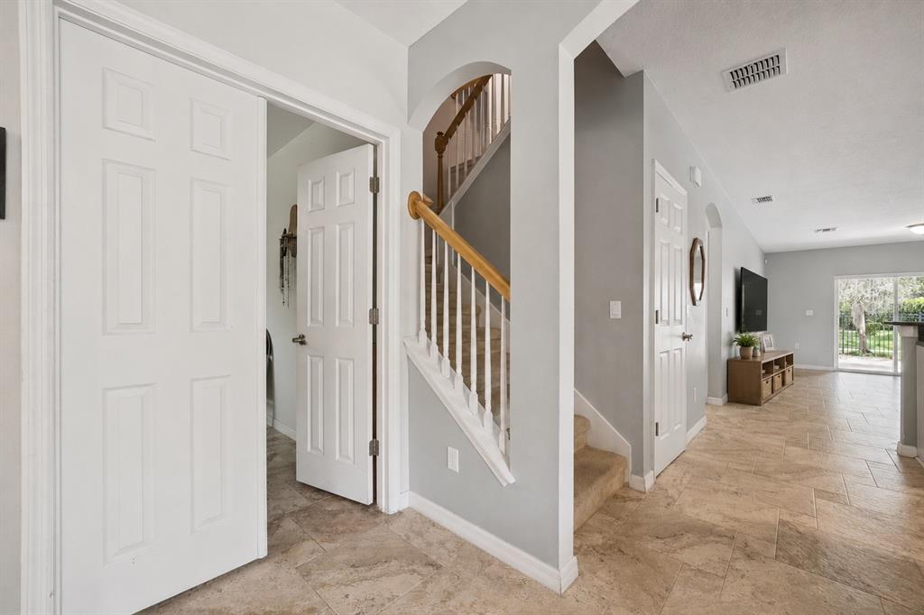 A tiled entryway features a staircase with a wooden handrail and white doors — 921 BENDING OAK TRAIL, WINTER GARDEN, FL