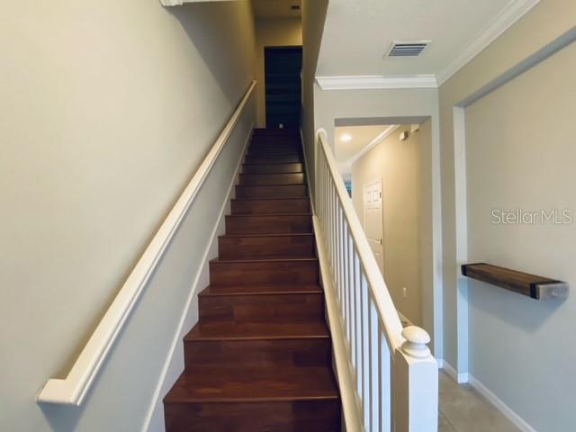 A staircase with dark wood treads and a white railing leads to an upper floor — 6842 40TH LANE N, PINELLAS PARK, FL
