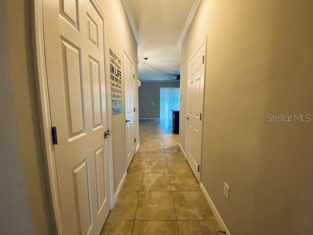 A hallway with tiled floors leads toward a living area with a sliding glass door — 6842 40TH LANE N, PINELLAS PARK, FL