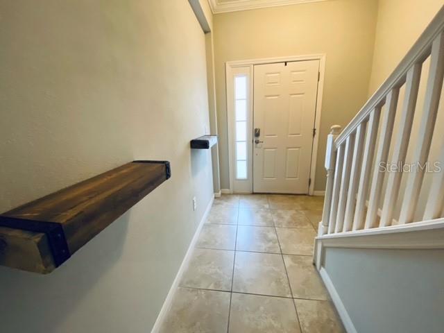 An entryway features a tiled floor, a white front door, and two rustic wooden wall shelves — 6842 40TH LANE N, PINELLAS PARK, FL