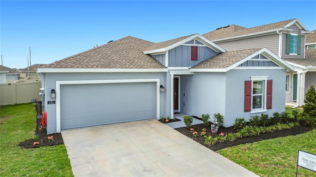 A single-story house with a gray stucco exterior, a two-car garage, and red shutters — 550 SEA TURTLE LANE, HAINES CITY, FL