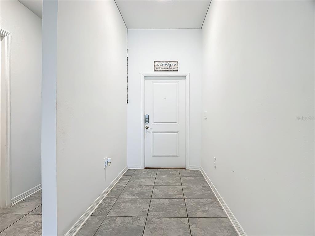 A tiled entryway features white walls, a single white door, and a family wall sign — 550 SEA TURTLE LANE, HAINES CITY, FL