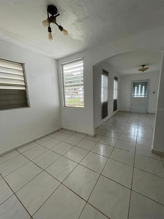An interior view shows a tiled room with louvered windows and an arched entryway — 51 CALLE PARQUE, AGUADILLA, PR