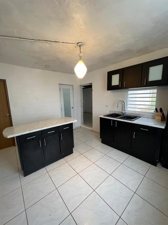 A kitchen features dark cabinets, a marble-look island, and white tile flooring — 51 CALLE PARQUE, AGUADILLA, PR