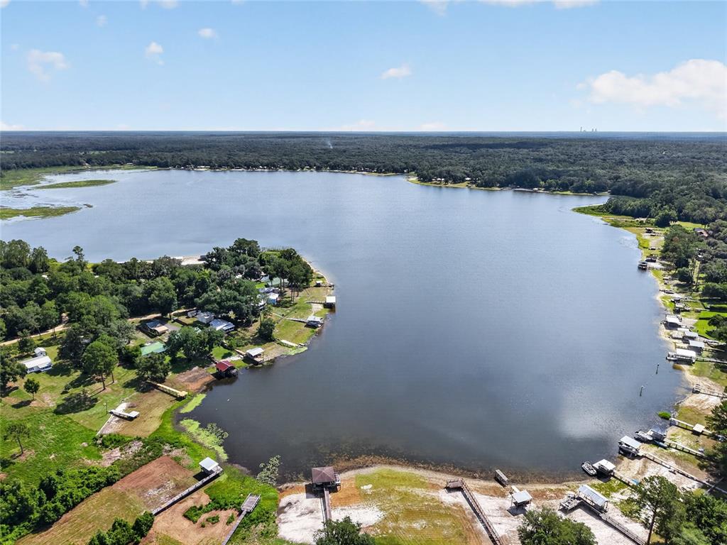 An aerial view shows a lake surrounded by trees, residential properties, and private boat docks — 148 LAKE SHORE TERRACE, INTERLACHEN, FL