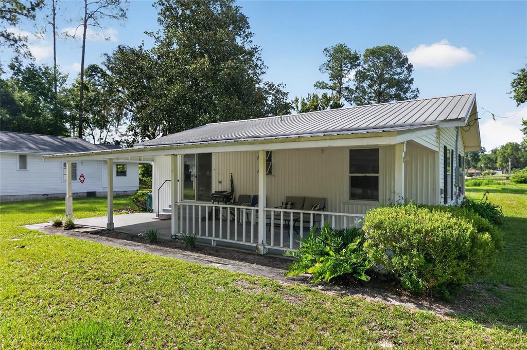 A white house with a metal roof features a large covered porch and green lawn — 148 LAKE SHORE TERRACE, INTERLACHEN, FL