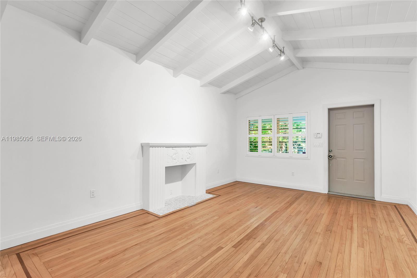 A living room features white walls, a vaulted ceiling with exposed beams, and hardwood floors — 776 NE 74th St # 0, Miami FL 33138, MIAMI, FL