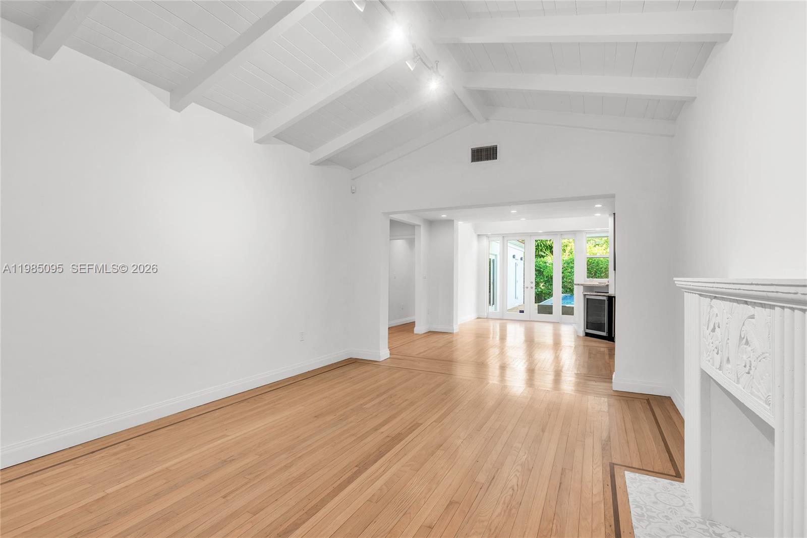 A living room features white vaulted ceilings, hardwood floors, and a white fireplace — 776 NE 74th St # 0, Miami FL 33138, MIAMI, FL