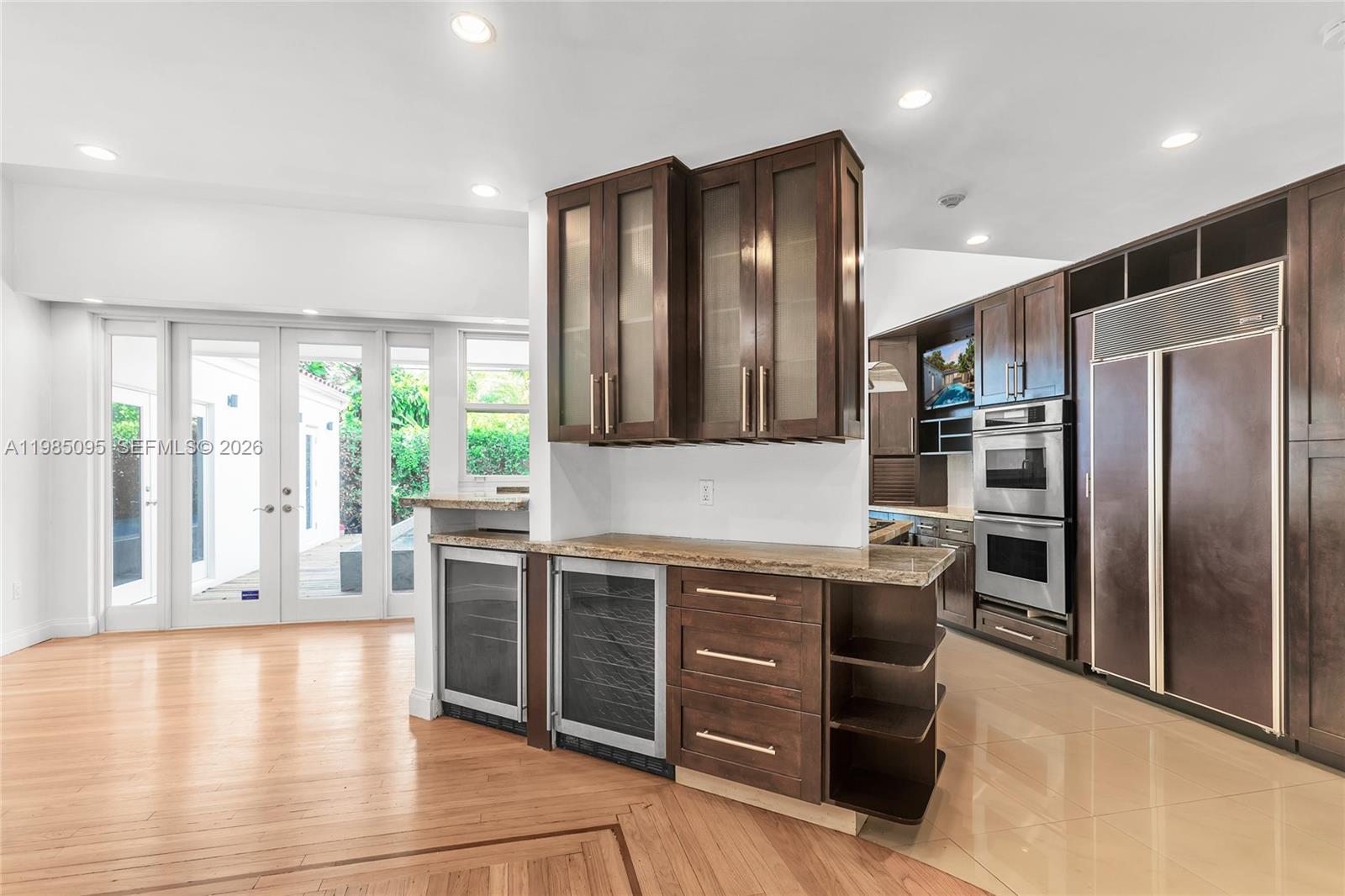A kitchen features dark wood cabinetry, stainless steel appliances, and a wine cooler island — 776 NE 74th St # 0, Miami FL 33138, MIAMI, FL