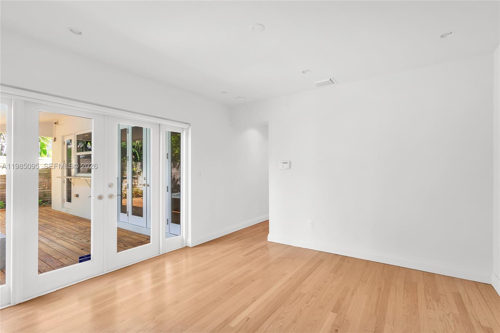 A bright, empty room features white walls, light hardwood floors, and glass-paned double doors — 776 NE 74th St # 0, Miami FL 33138, MIAMI, FL