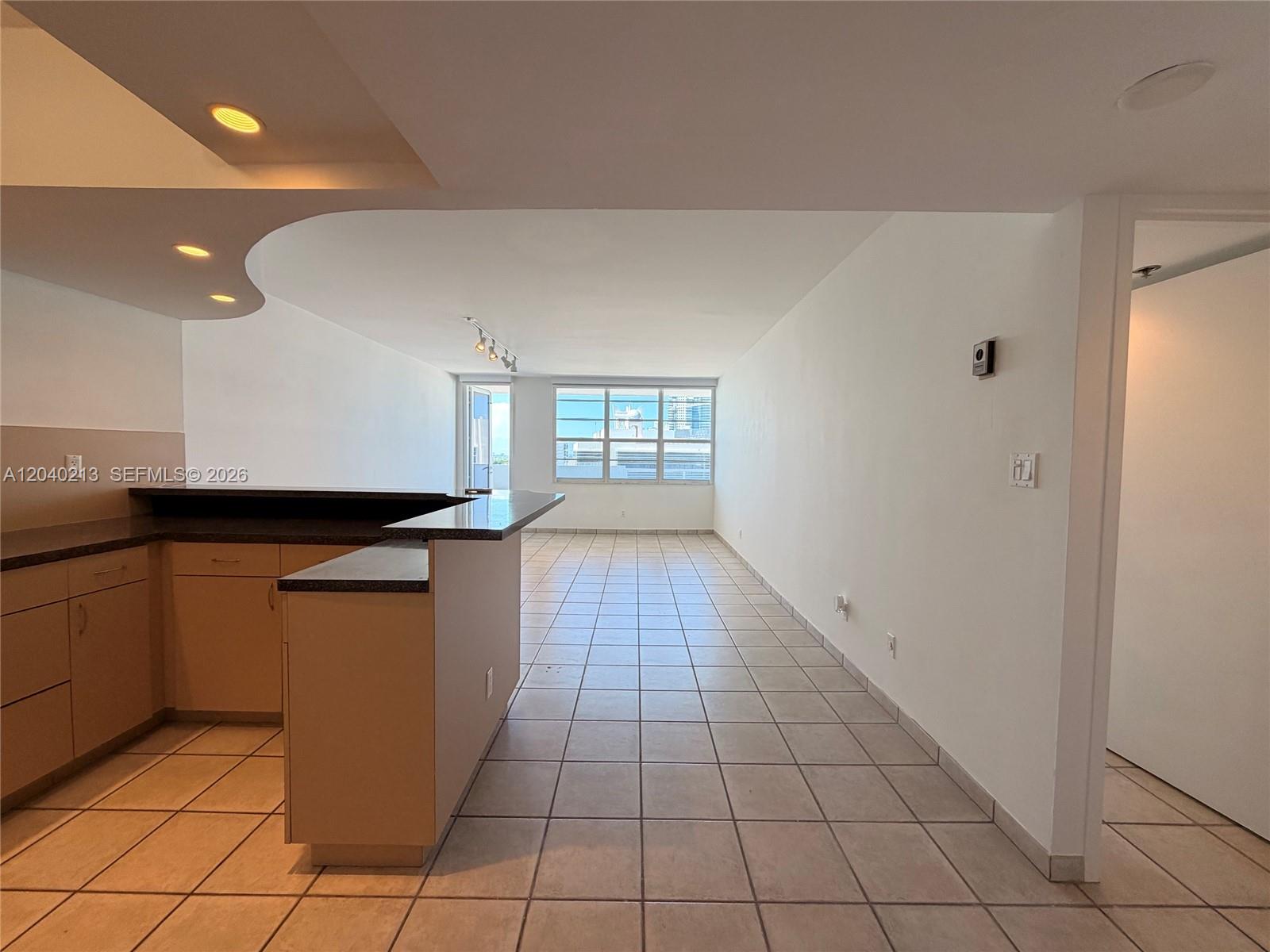 An open-concept living area features a kitchen with a breakfast bar and tiled floors — 100 Lincoln Rd # 1410, Miami Beach FL 33139, MIAMI BEACH, FL