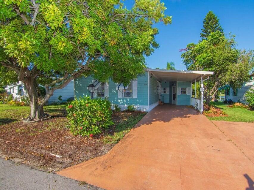 A light blue mobile home with a carport and a large tree in the front yard — 6910 SE Morningside Drive, Stuart FL 34997, STUART, FL