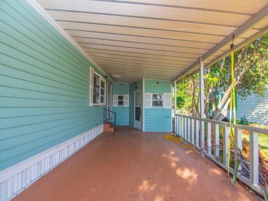A covered patio with light blue siding, a concrete floor, and a white wooden railing — 6910 SE Morningside Drive, Stuart FL 34997, STUART, FL