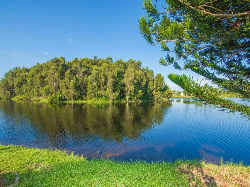 A view of a calm lake reflecting a dense cluster of trees under a blue sky — 6910 SE Morningside Drive, Stuart FL 34997, STUART, FL