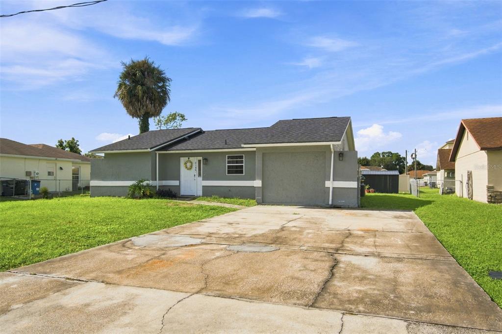 A single-story house with a gray exterior, a front-facing garage, and a concrete driveway — 618 CARIBOU COURT, POINCIANA, FL