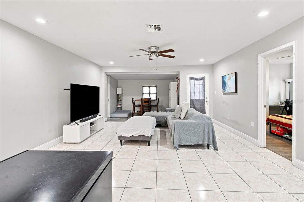 A living room with light tile flooring, a grey sectional sofa, and a television console — 618 CARIBOU COURT, POINCIANA, FL
