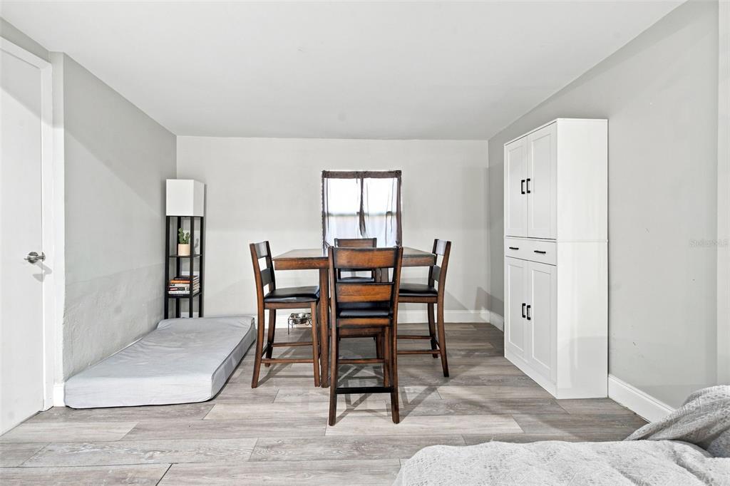 A dining area features a wooden table with four chairs, a white cabinet, and flooring — 618 CARIBOU COURT, POINCIANA, FL