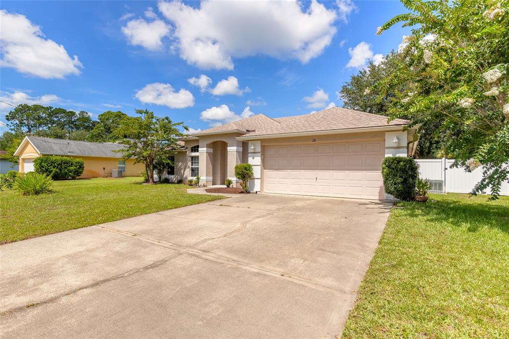 A single-story house with a beige exterior, a two-car garage, and a concrete driveway — 26 EDGELY LANE, PALM COAST, FL