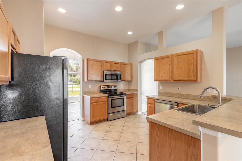 A kitchen features wood cabinets, stainless steel appliances, tan countertops, and light-colored tile flooring — 26 EDGELY LANE, PALM COAST, FL