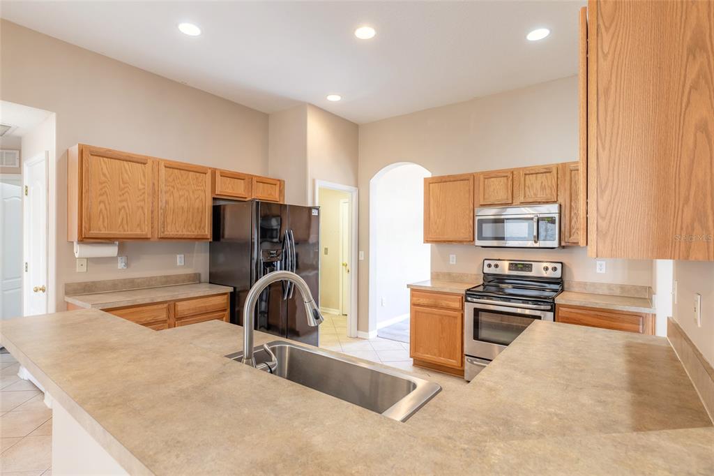 A kitchen features oak cabinets, laminate countertops, a stainless steel sink, and black appliances — 26 EDGELY LANE, PALM COAST, FL