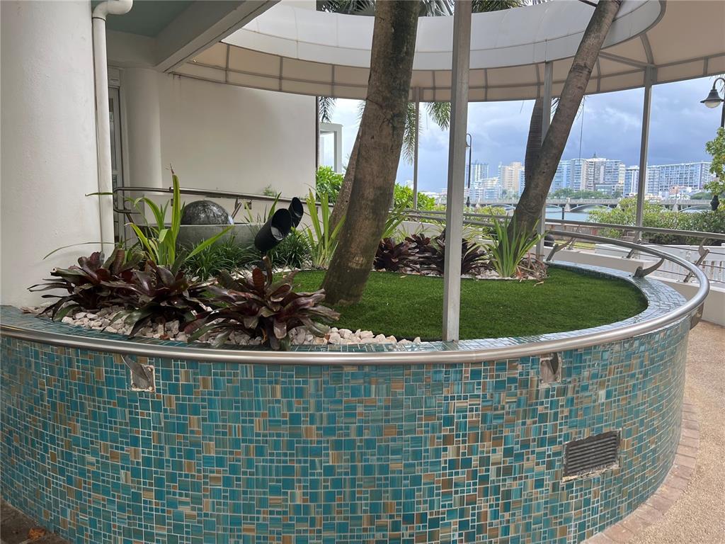 A curved, tiled planter bed with artificial grass and trees sits on an outdoor patio — 15 SAN GERONIMO UNIT 208, SAN JUAN, PR