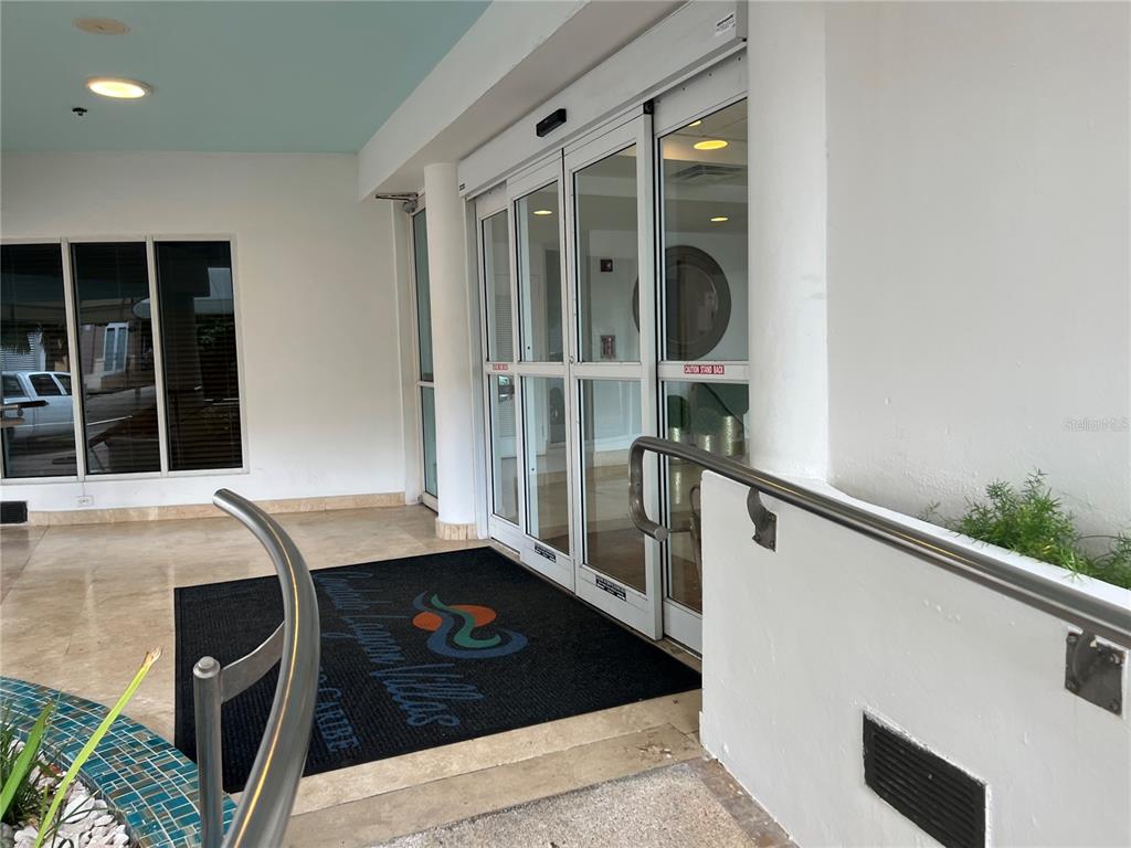 The entrance to a building features glass sliding doors, a branded floor mat, and railings — 15 SAN GERONIMO UNIT 208, SAN JUAN, PR