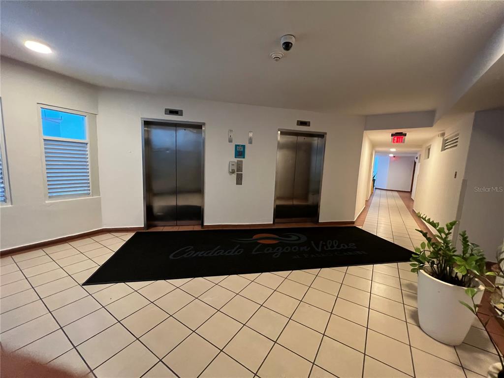 An elevator lobby with tiled floors, a black logo rug, and a hallway leading to an exit — 15 SAN GERONIMO UNIT 208, SAN JUAN, PR
