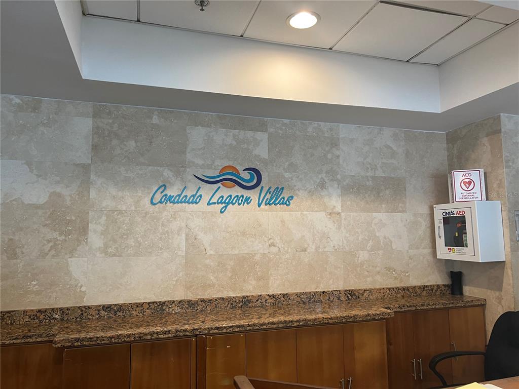 A lobby wall features the Condado Lagoon Villas logo, stone tile, and an AED cabinet — 15 SAN GERONIMO UNIT 208, SAN JUAN, PR