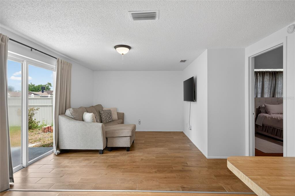 A living room features wood-look tile flooring, a beige sectional sofa, and a wall-mounted television — 6401 REGATTA COURT, TAMPA, FL