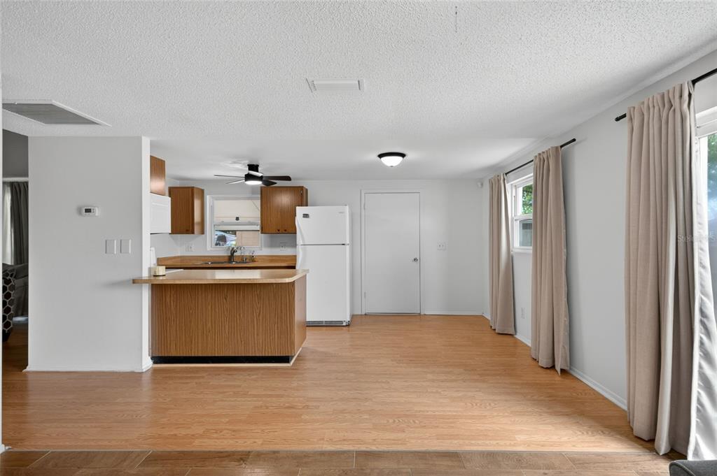 An open-concept kitchen and dining area featuring wood-look flooring, light walls, and a breakfast bar — 6401 REGATTA COURT, TAMPA, FL