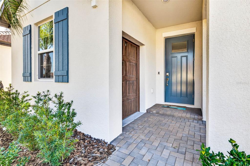 A front entryway features a blue door, a wooden side door, and a brick paver porch — 17245 STAR BANKS ST, WIMAUMA, FL