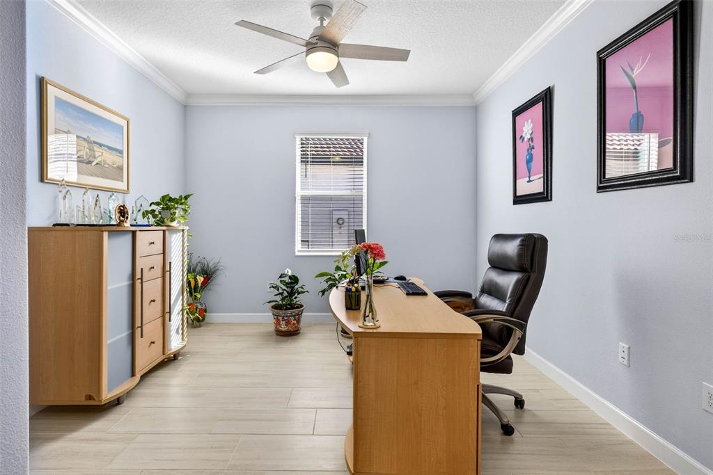 A home office features a wooden desk, a black leather chair, and light tile flooring — 17245 STAR BANKS ST, WIMAUMA, FL