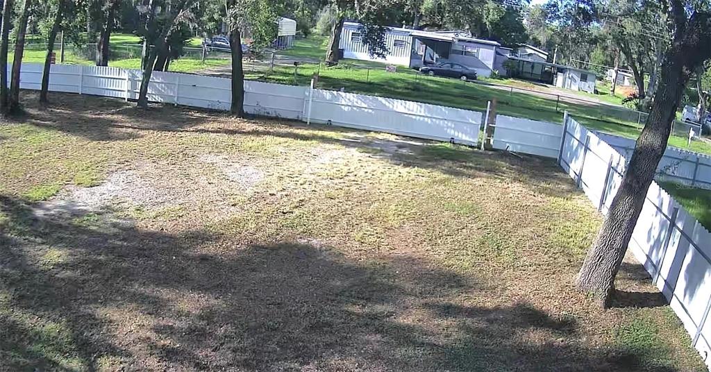 A large, grassy backyard features a white vinyl privacy fence and several mature trees — 11310 BRIGHTRIDGE DRIVE, SEFFNER, FL