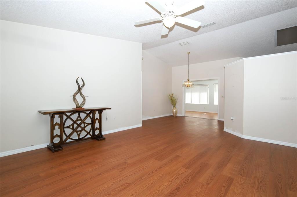 A living room features wood-look flooring, a ceiling fan, and a decorative console table — 610 YORKTOWN DRIVE, LEESBURG, FL