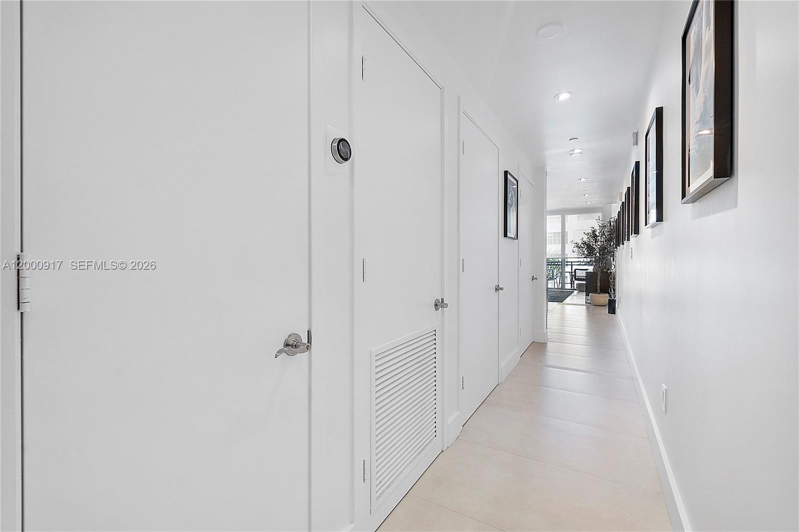 A bright, white hallway features tiled floors, multiple doors, and a series of framed pictures — 6000 Collins Ave # 527, Miami Beach FL 33140, MIAMI BEACH, FL